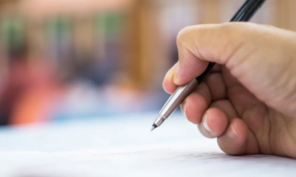 Hand holding pen writing on paper